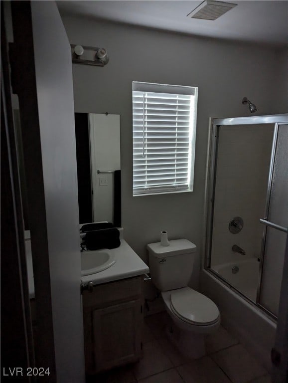 full bathroom featuring combined bath / shower with glass door, vanity, tile patterned floors, and toilet