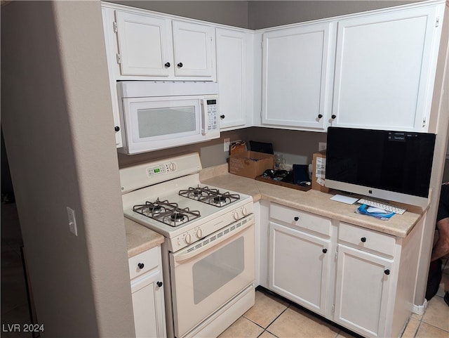 kitchen featuring white cabinets, light tile patterned floors, and white appliances