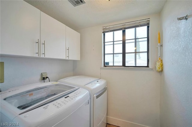 clothes washing area with cabinets, a textured ceiling, and separate washer and dryer