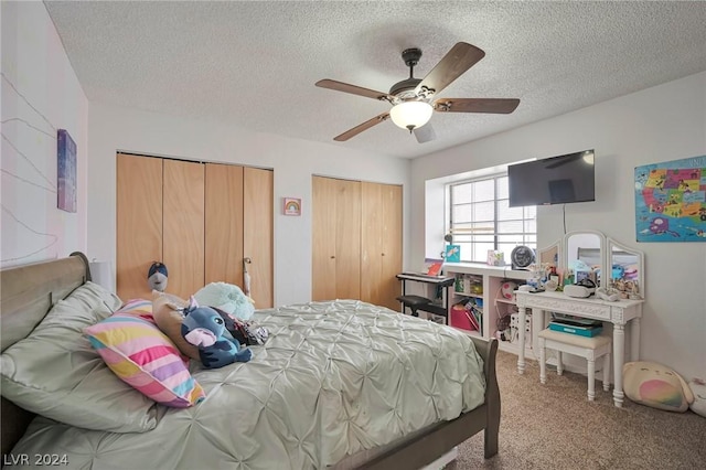 carpeted bedroom with ceiling fan, a textured ceiling, and multiple closets