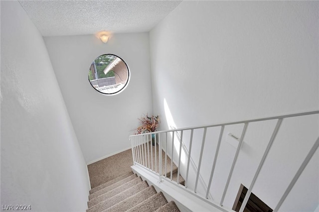 stairs featuring carpet floors and a textured ceiling