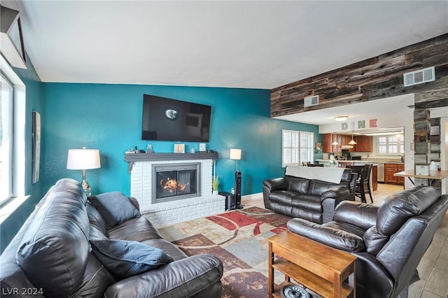 living room featuring wood walls, a fireplace, a healthy amount of sunlight, and light wood-type flooring