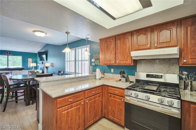 kitchen with gas stove, light stone counters, light hardwood / wood-style flooring, kitchen peninsula, and pendant lighting