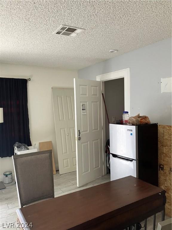 kitchen with stainless steel fridge, refrigerator, and a textured ceiling