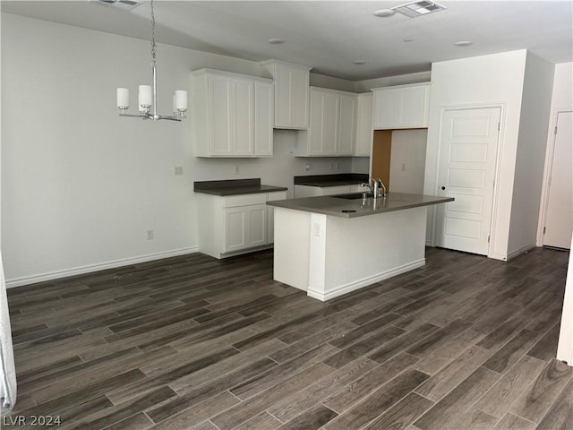 kitchen featuring white cabinets, dark hardwood / wood-style floors, a notable chandelier, and an island with sink