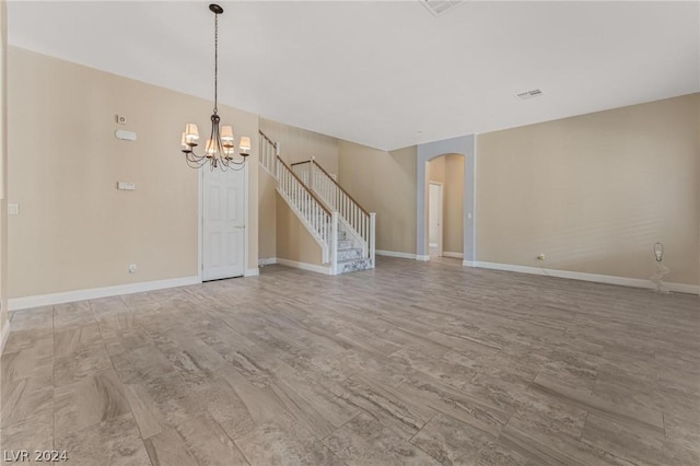 unfurnished living room with a chandelier and light wood-type flooring