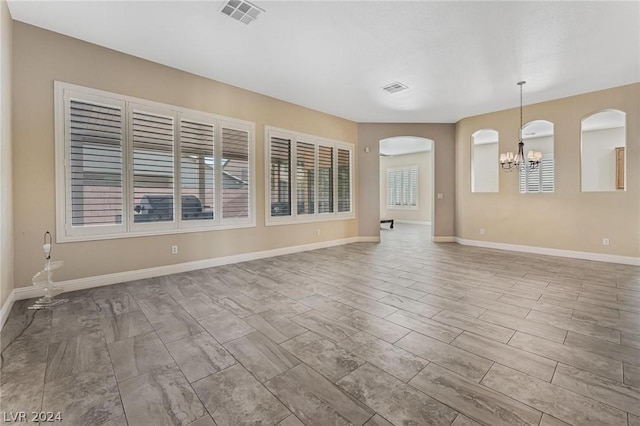 spare room featuring light wood-type flooring and an inviting chandelier