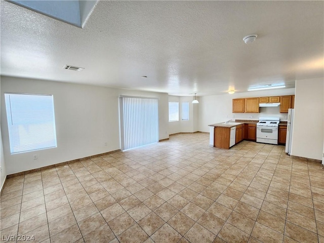 kitchen featuring a textured ceiling, white appliances, and kitchen peninsula