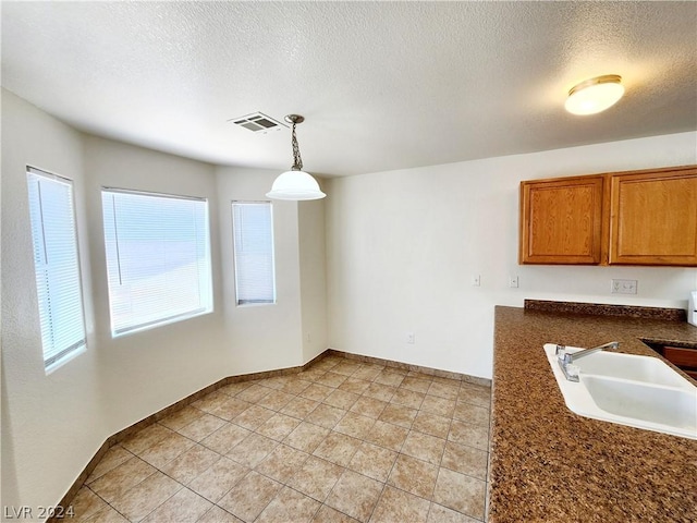 unfurnished dining area with sink, light tile patterned floors, and a textured ceiling