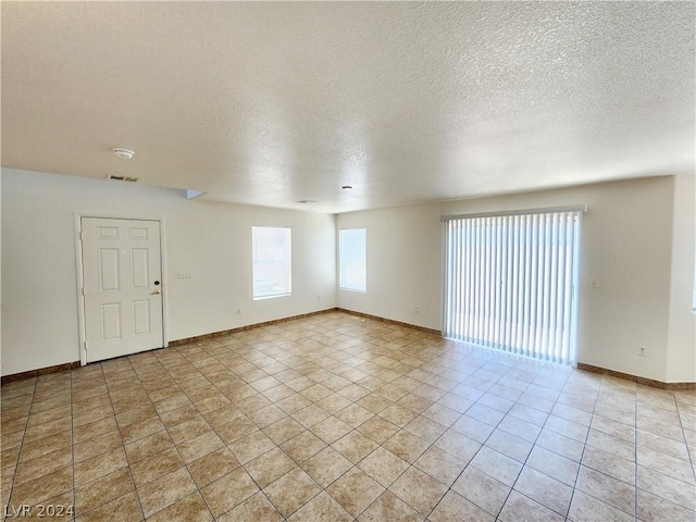 spare room featuring light tile patterned floors and a textured ceiling