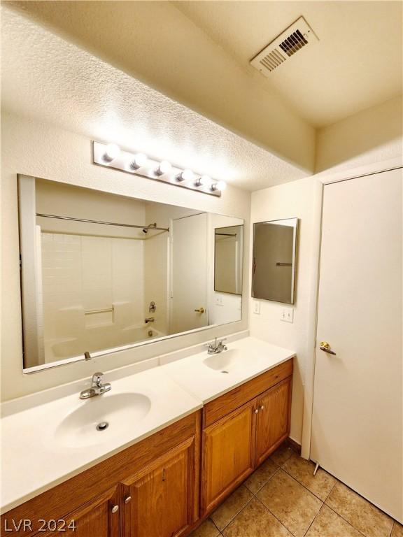 bathroom with tile patterned floors, vanity, shower / washtub combination, and a textured ceiling