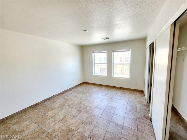 unfurnished bedroom featuring a closet, light tile patterned floors, and a textured ceiling