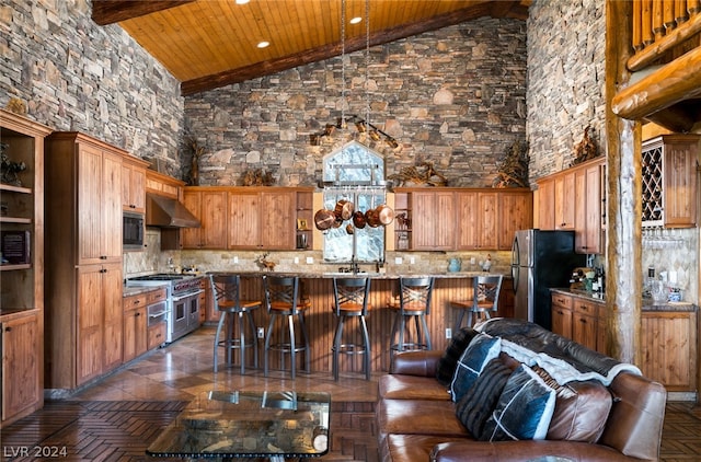 kitchen with high vaulted ceiling, wooden ceiling, wall chimney range hood, and stainless steel appliances