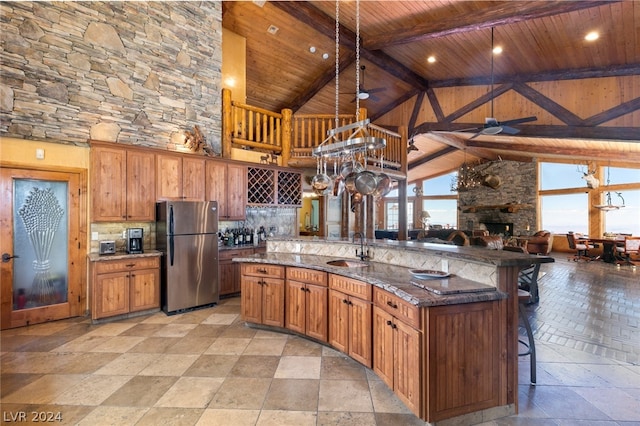 kitchen with ceiling fan, stainless steel fridge, backsplash, high vaulted ceiling, and a kitchen bar