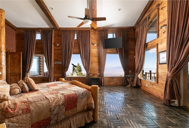 bedroom with beamed ceiling, dark parquet flooring, wood walls, and ceiling fan