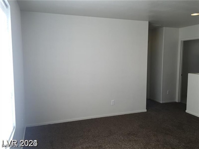 unfurnished room featuring dark colored carpet