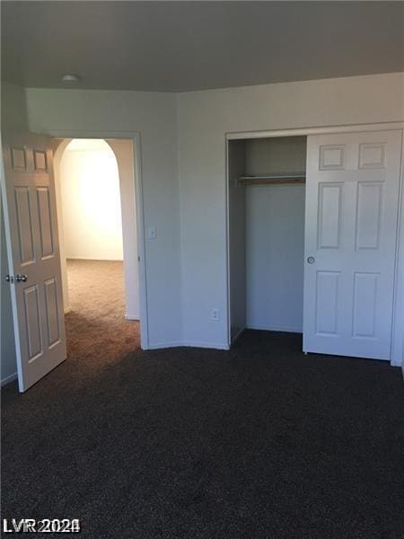 unfurnished bedroom featuring dark colored carpet and a closet