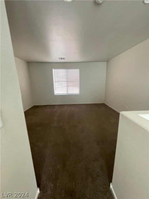 unfurnished room featuring dark carpet