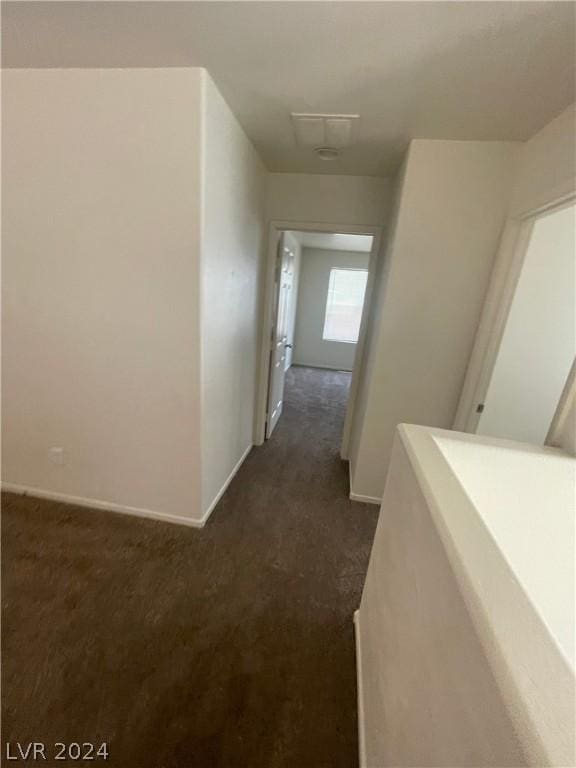 hallway featuring dark colored carpet