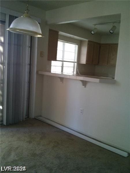 kitchen with hanging light fixtures, carpet flooring, a kitchen breakfast bar, and kitchen peninsula