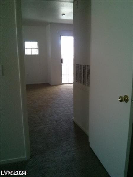 hall featuring dark colored carpet