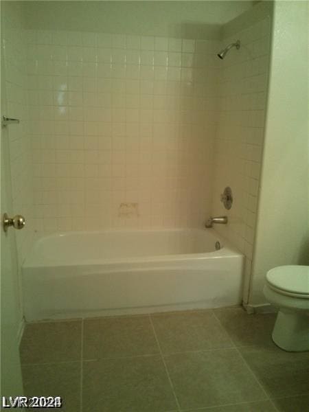 bathroom featuring tiled shower / bath, tile patterned floors, and toilet