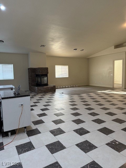 unfurnished living room featuring lofted ceiling and a wood stove