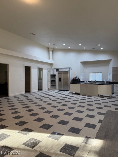 basement with tile patterned flooring and stainless steel fridge with ice dispenser