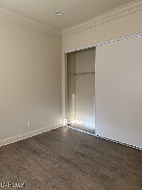 unfurnished bedroom featuring ornamental molding, a closet, and dark hardwood / wood-style flooring