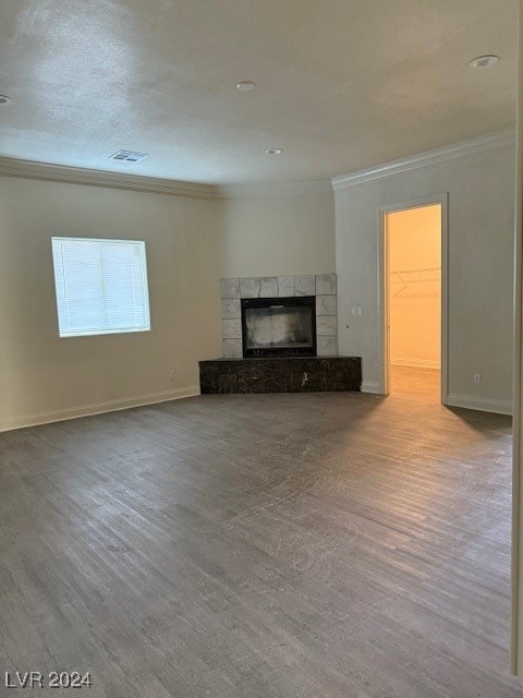 unfurnished living room featuring light hardwood / wood-style floors, crown molding, and a tiled fireplace