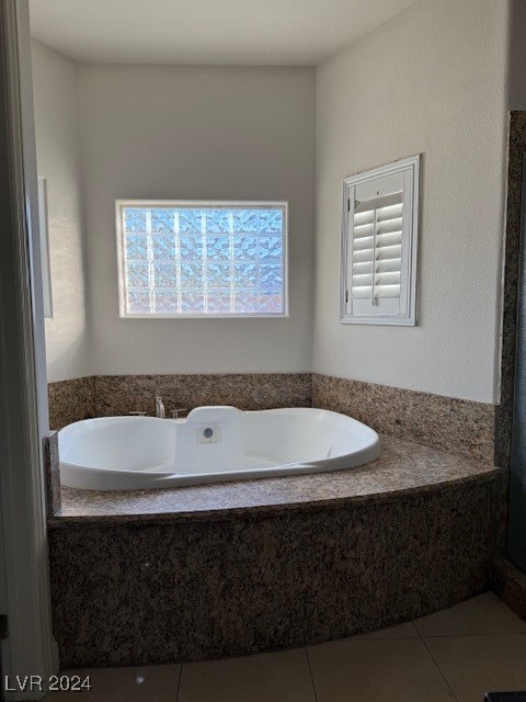 bathroom featuring tile patterned flooring and a relaxing tiled tub