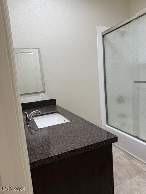 bathroom with vanity, tile patterned flooring, and combined bath / shower with glass door