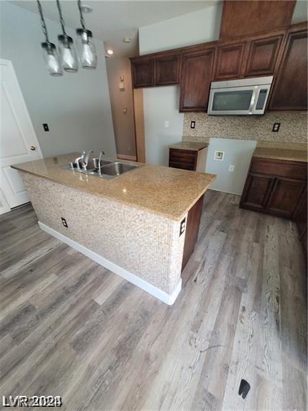 kitchen with sink, a center island, light hardwood / wood-style floors, decorative light fixtures, and decorative backsplash