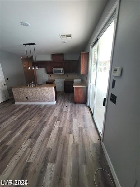 kitchen with refrigerator, dark wood-type flooring, a kitchen island, and hanging light fixtures