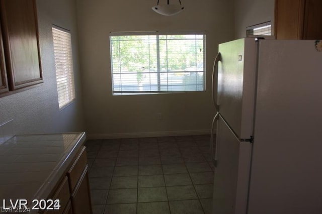 kitchen with tile countertops, tile patterned flooring, and white fridge