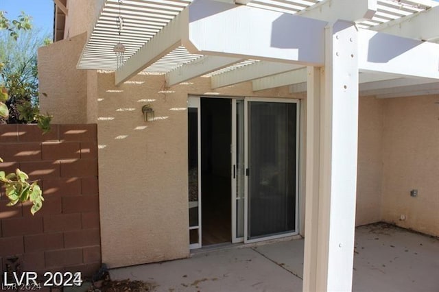 property entrance featuring a patio and a pergola