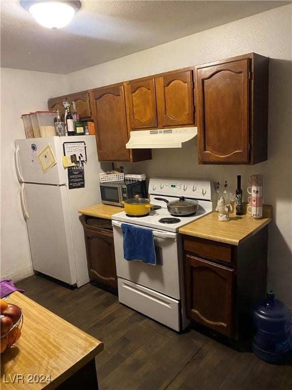 kitchen featuring dark wood-style floors, under cabinet range hood, light countertops, and white appliances