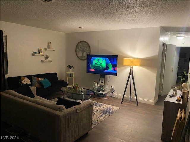 living area featuring finished concrete flooring, a textured ceiling, and baseboards