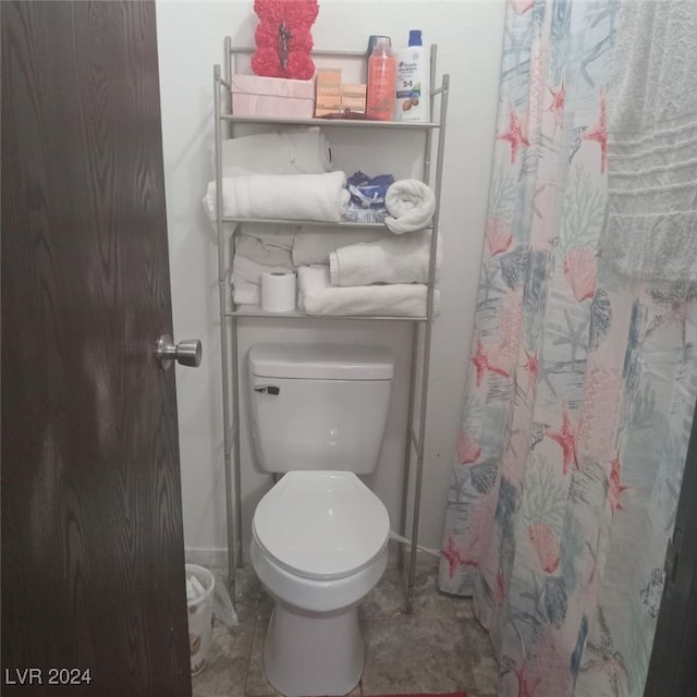 bathroom featuring toilet, a shower with curtain, and baseboards