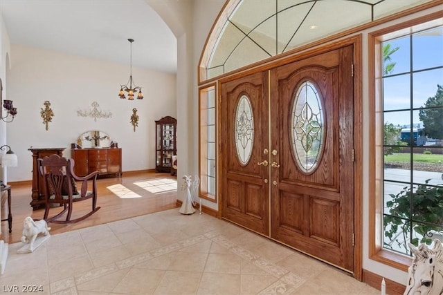 entryway with light tile patterned floors and a notable chandelier