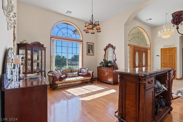 sitting room featuring a high ceiling, a notable chandelier, and light hardwood / wood-style flooring