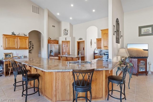 kitchen with stainless steel fridge with ice dispenser, a kitchen breakfast bar, sink, and kitchen peninsula