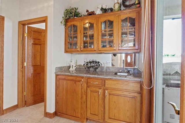 bar featuring sink, light tile patterned floors, and light stone countertops