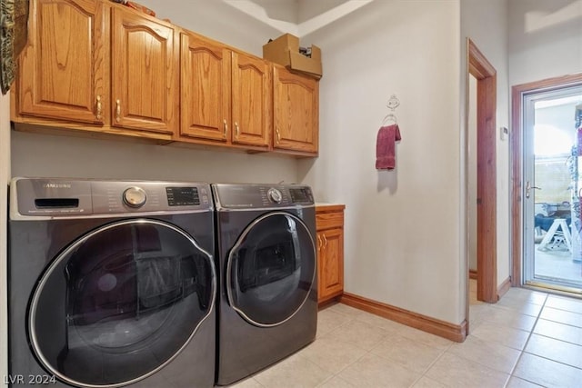 laundry room with cabinets, washing machine and dryer, and light tile patterned floors