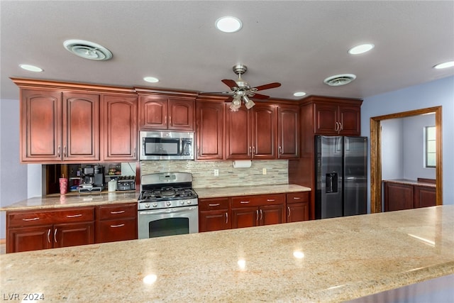 kitchen with ceiling fan, stainless steel appliances, backsplash, and light stone countertops