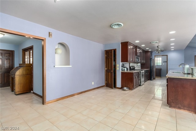 kitchen with dark brown cabinets, ceiling fan, stainless steel appliances, light tile floors, and sink