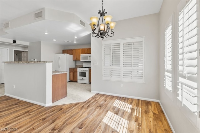 kitchen featuring light hardwood / wood-style flooring, white appliances, plenty of natural light, and decorative light fixtures