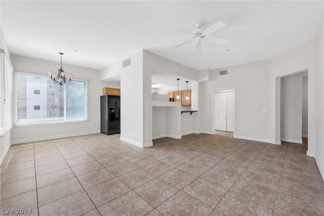 unfurnished living room with ceiling fan with notable chandelier and light tile patterned flooring