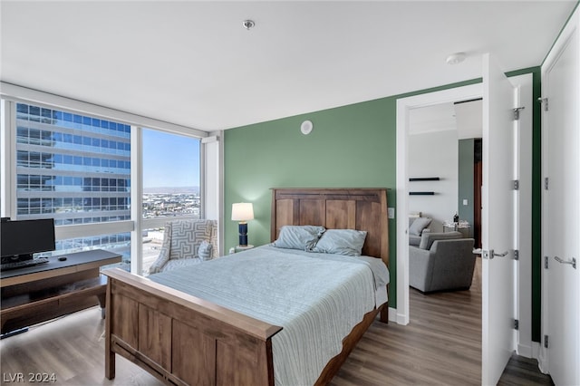 bedroom with floor to ceiling windows and dark hardwood / wood-style flooring