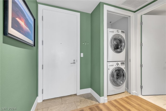 washroom with stacked washer and dryer and light tile floors